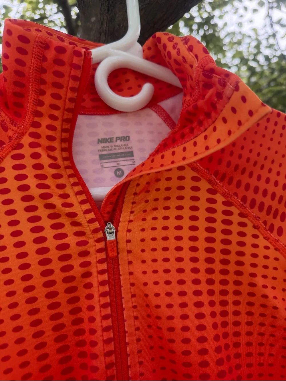 The Nike Pro Hyperwarm half-zip running top features a vibrant orange and red